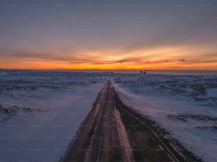 Die Sonne geht über einer verschneiten Straße unter