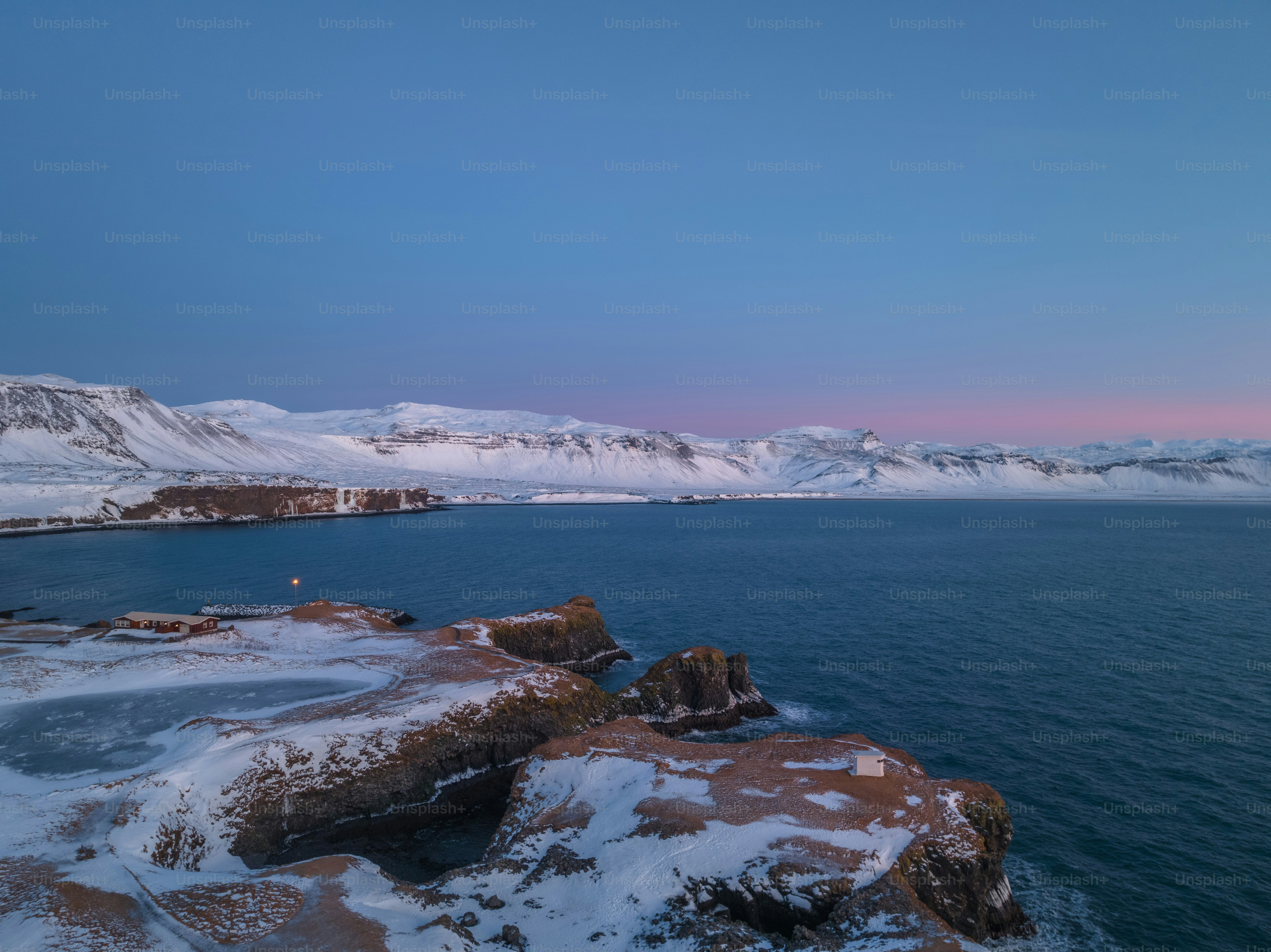 a body of water surrounded by snow covered mountains