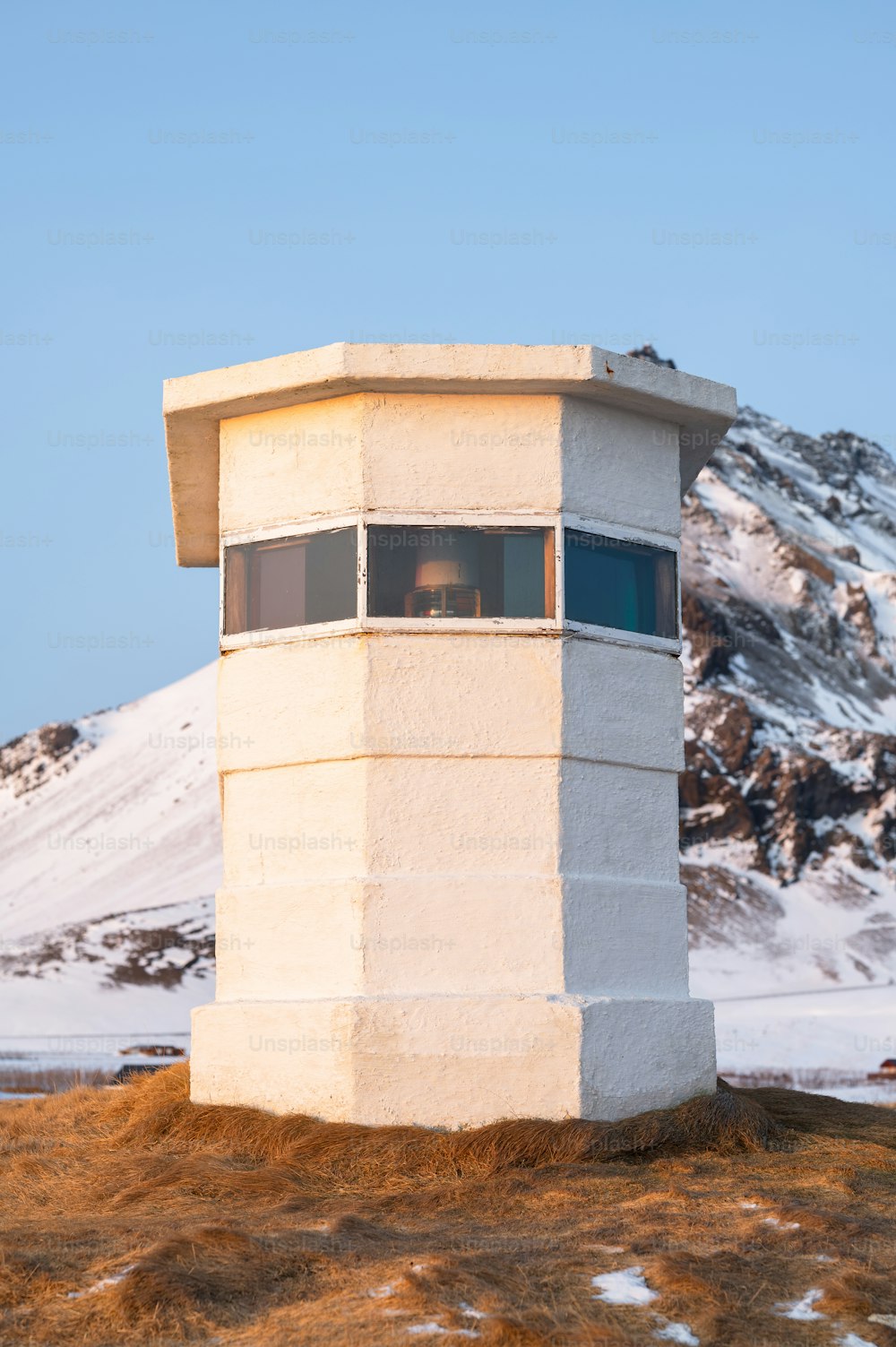 una torre blanca sentada en la cima de una colina cubierta de nieve