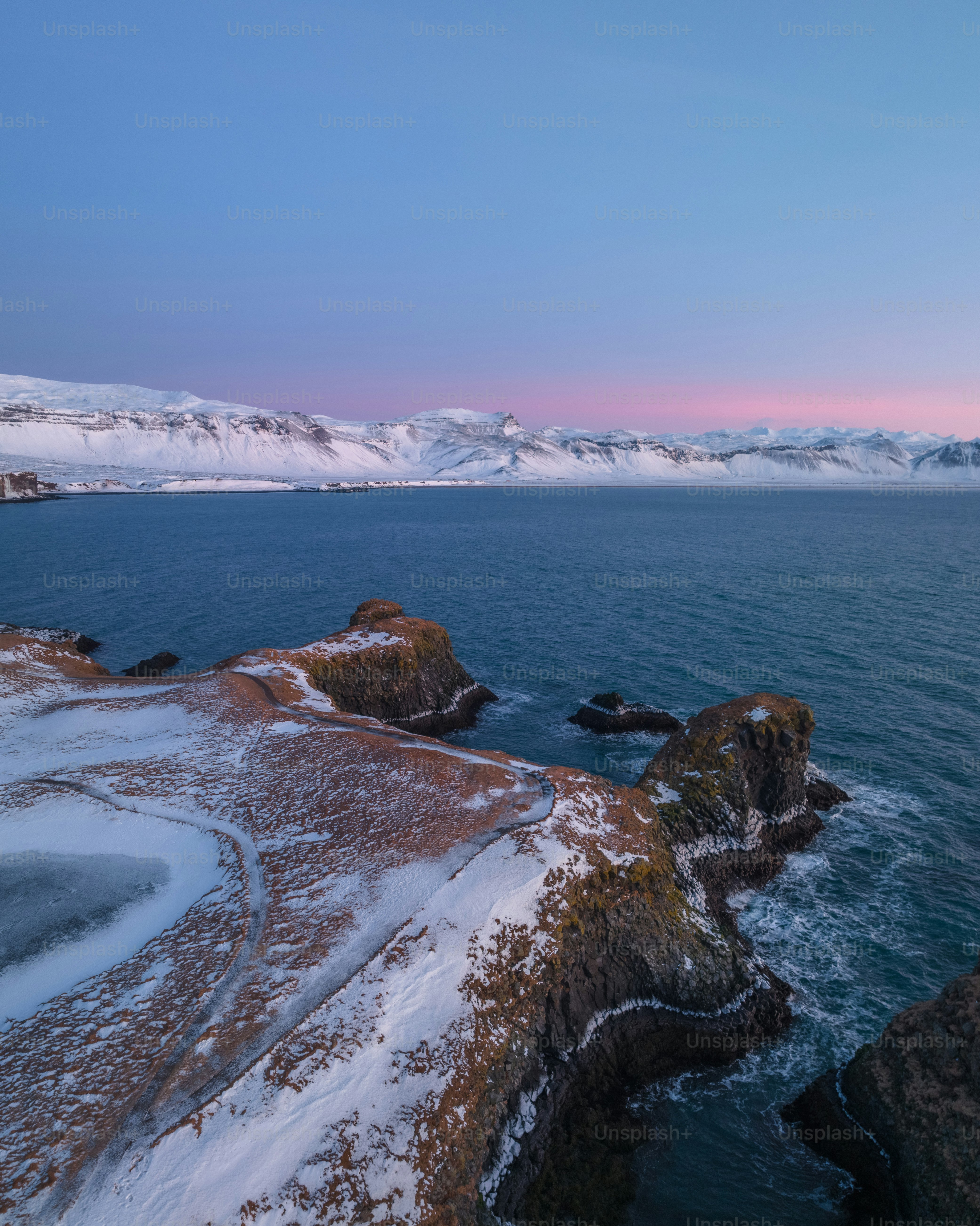 a body of water surrounded by snow covered mountains