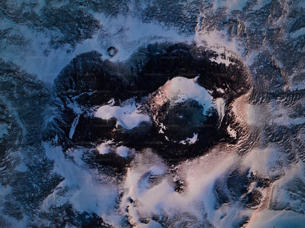 an aerial view of snow covered rocks and water