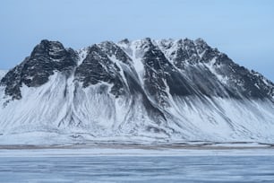 una grande montagna coperta di neve accanto a uno specchio d'acqua