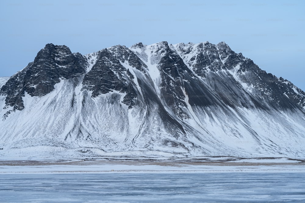 Una gran montaña cubierta de nieve junto a un cuerpo de agua