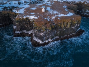 uma vista aérea de um farol em um afloramento rochoso no oceano