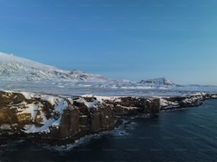 Una montagna innevata con uno specchio d'acqua di fronte