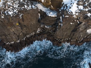 an aerial view of a rocky coastline with snow on the rocks
