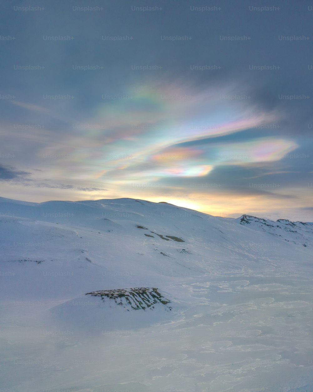 a rainbow in the sky over a snow covered mountain