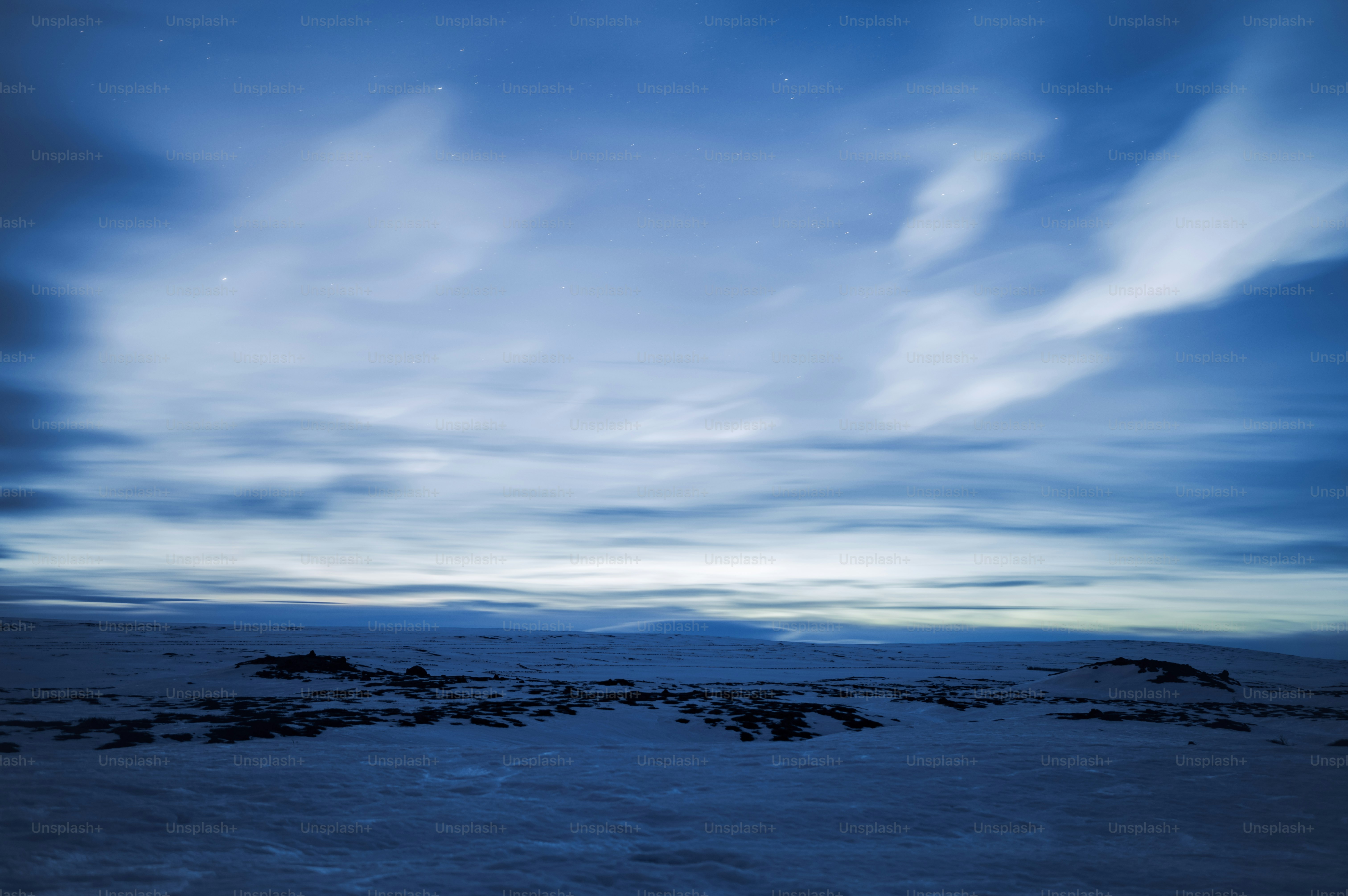 Un campo cubierto de nieve con un cielo lleno de nubes