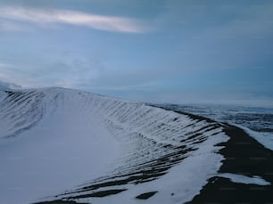 a mountain covered in snow under a cloudy sky