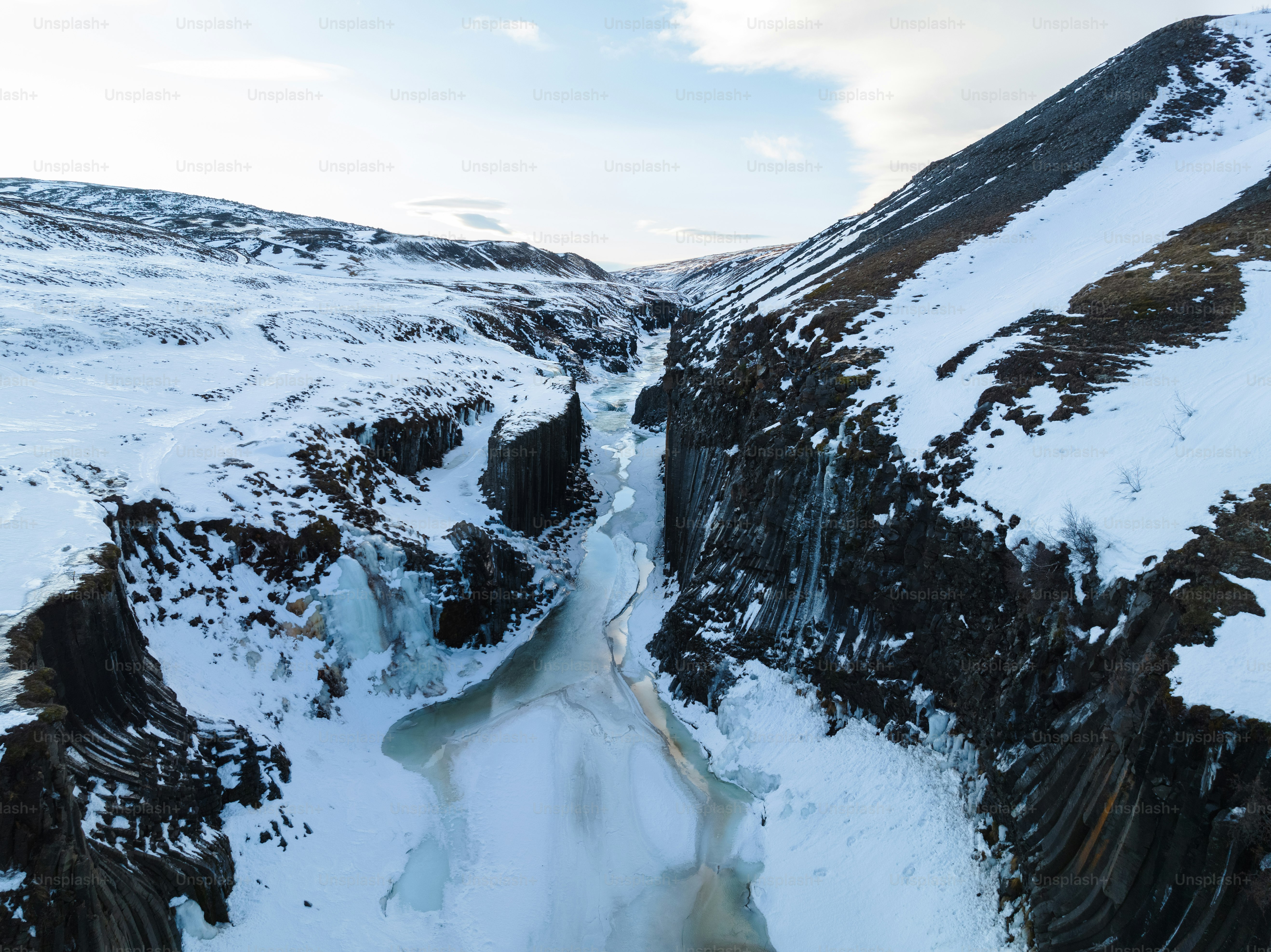 a mountain side with a stream of water in the middle of it