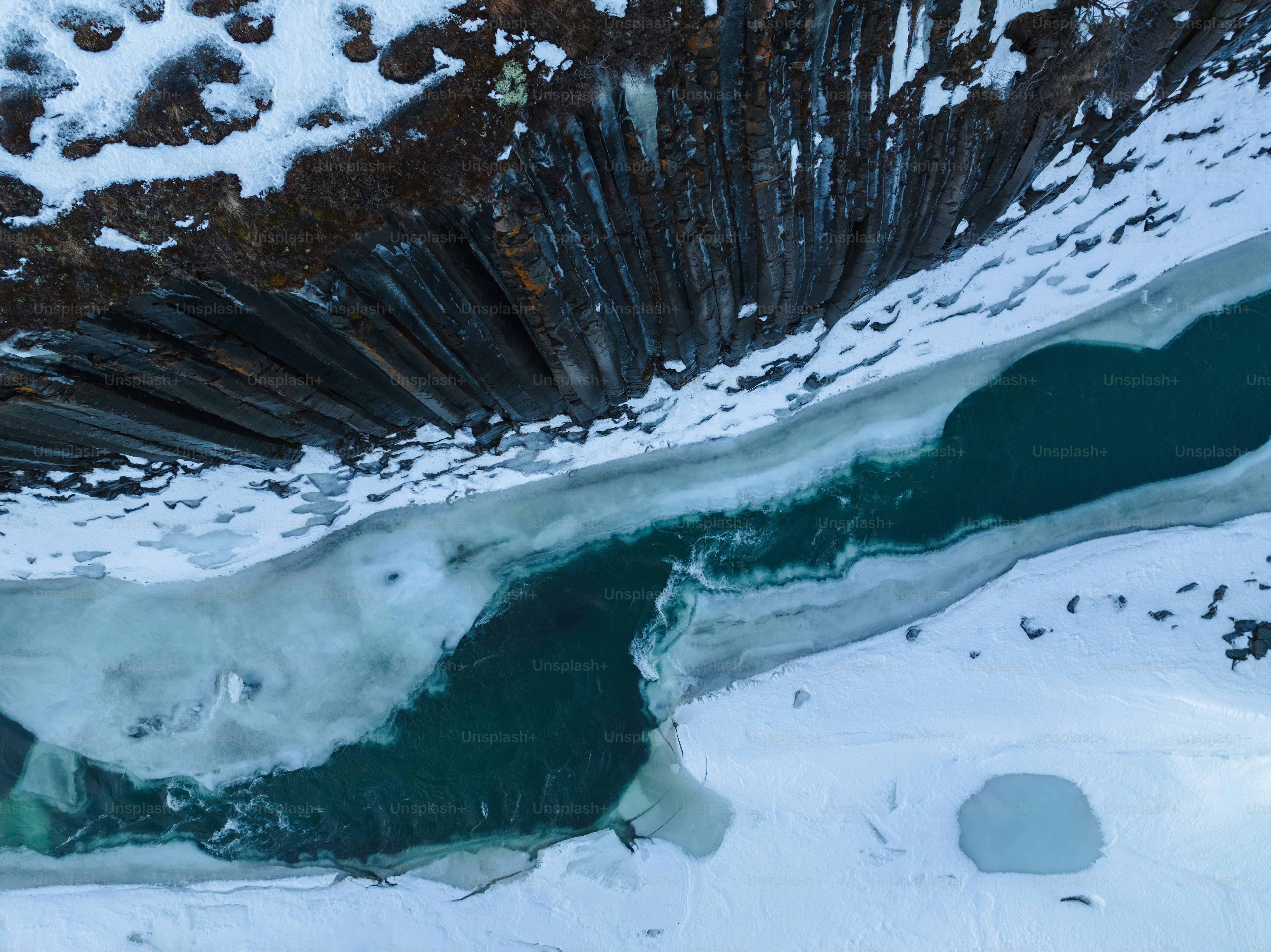 an aerial view of a river in the snow