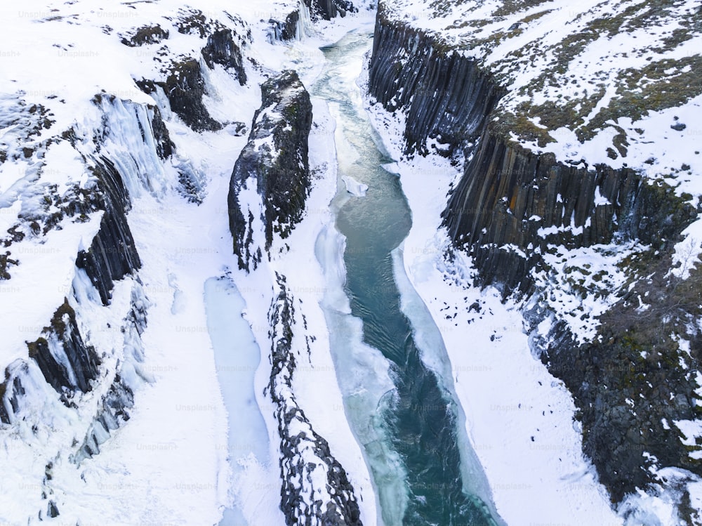 an aerial view of a river running through a snow covered mountain