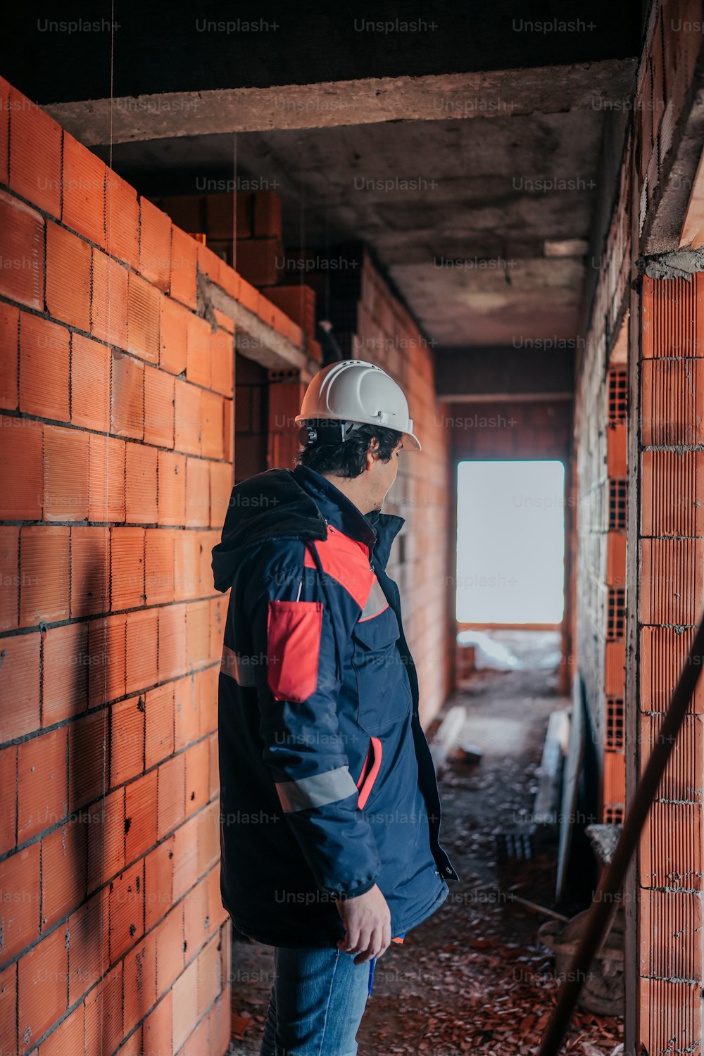 a man wearing a hard hat standing in front of a brick wall