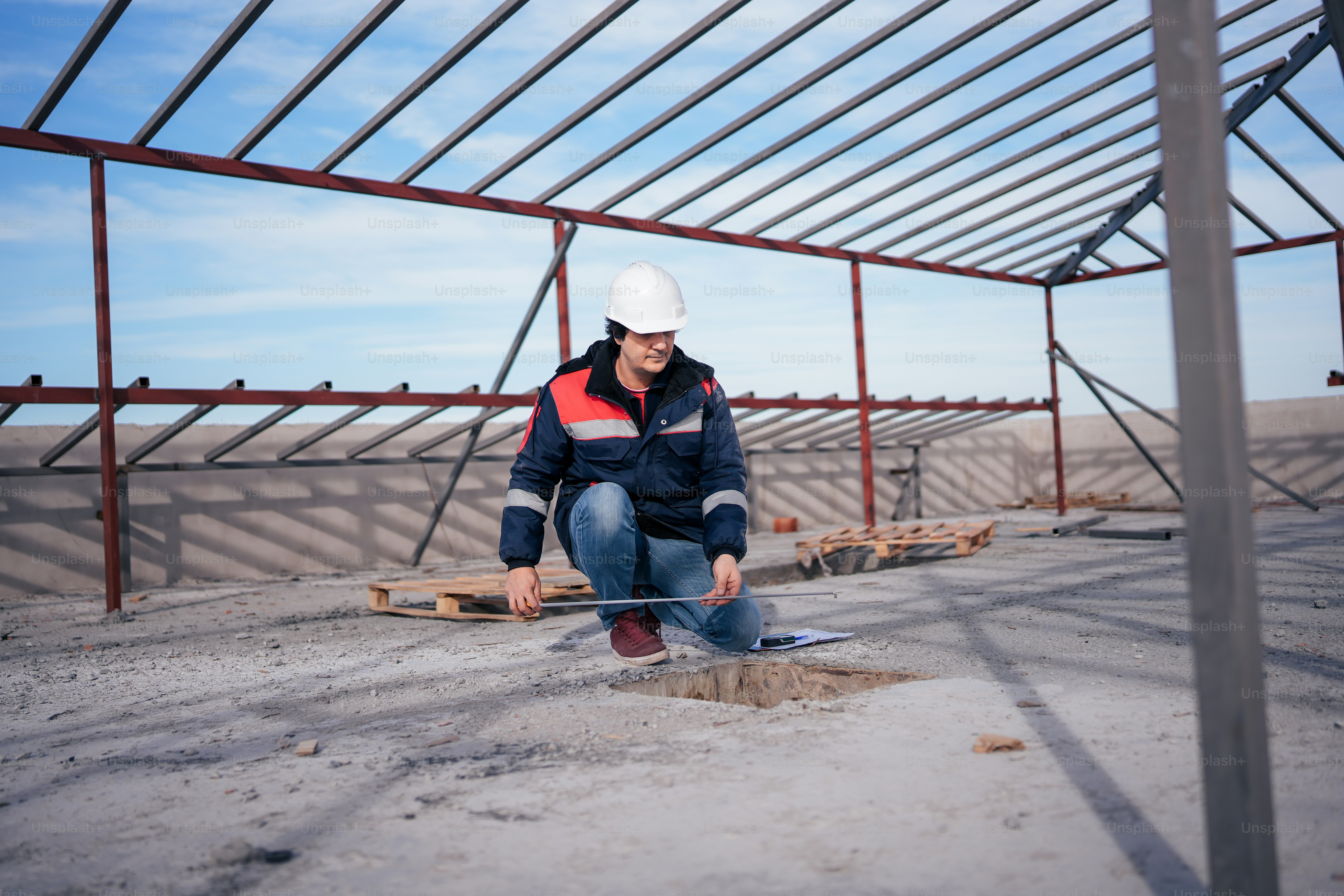 a man in a hard hat kneeling down on the ground