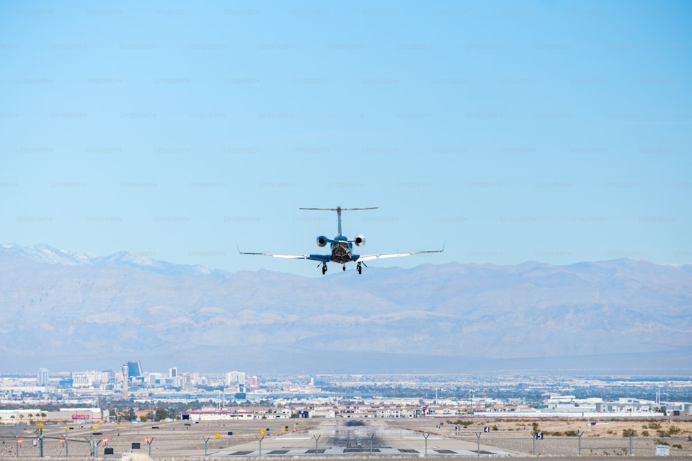 an airplane flying over a city with mountains in the background