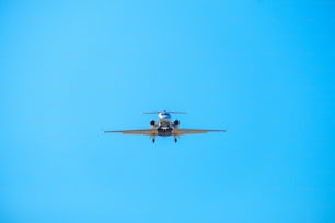 a small airplane flying through a blue sky