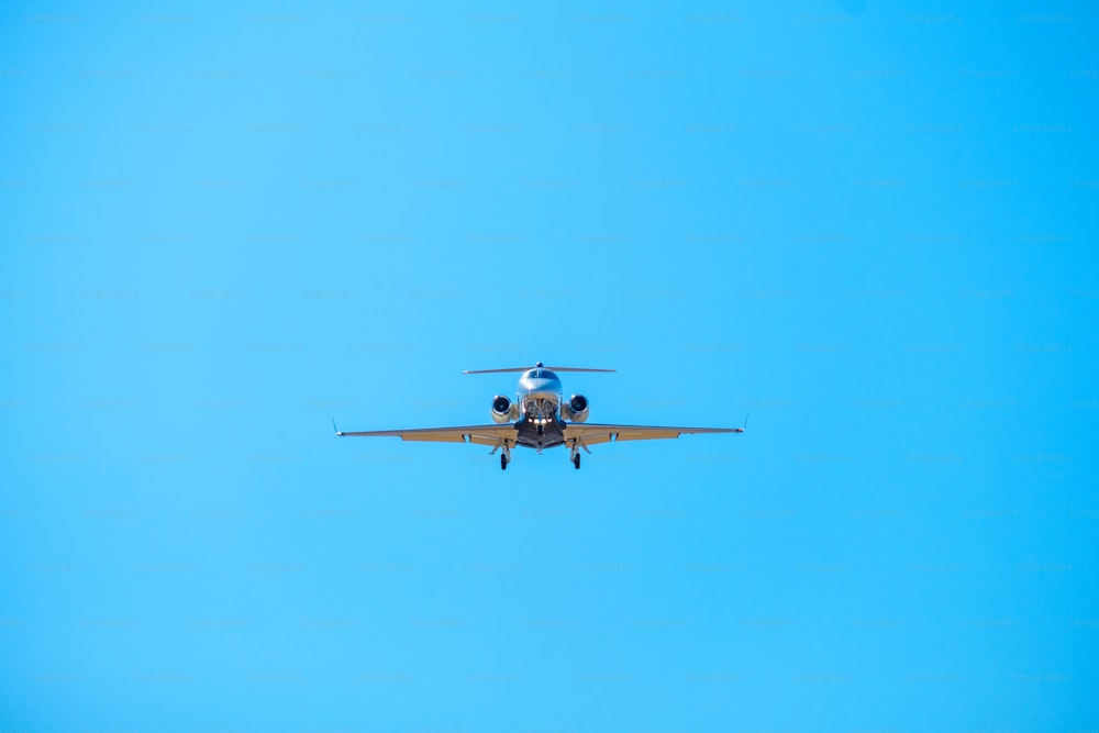 a small airplane flying through a blue sky