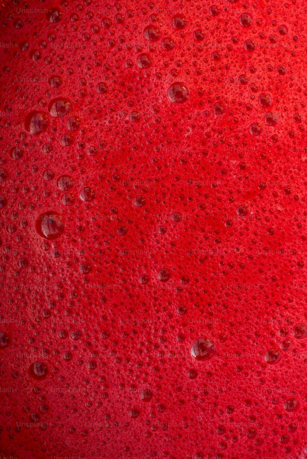 un primer plano de una sustancia roja con gotas de agua