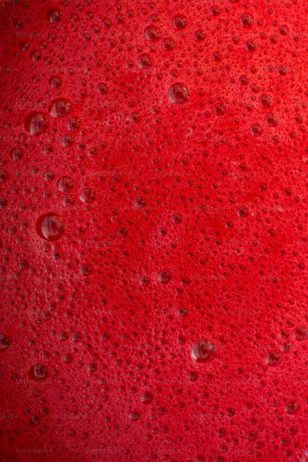 a close up of a red substance with drops of water