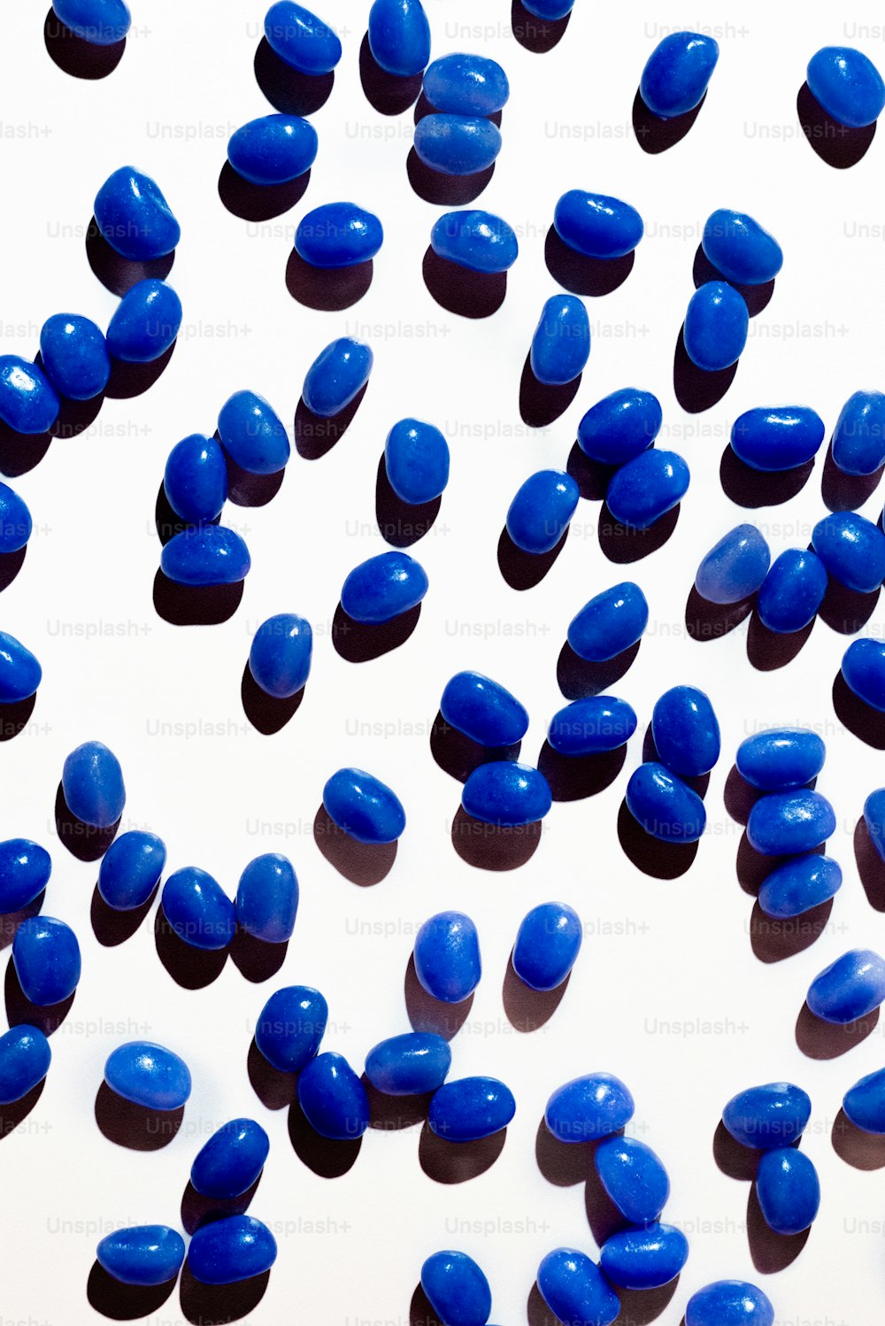 白い表面に多くの青い錠剤が散らばっています