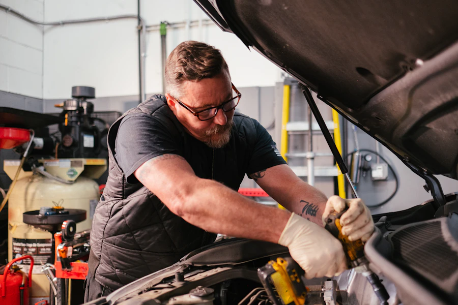 Mechanic working under the bonnet of a car in a workshop