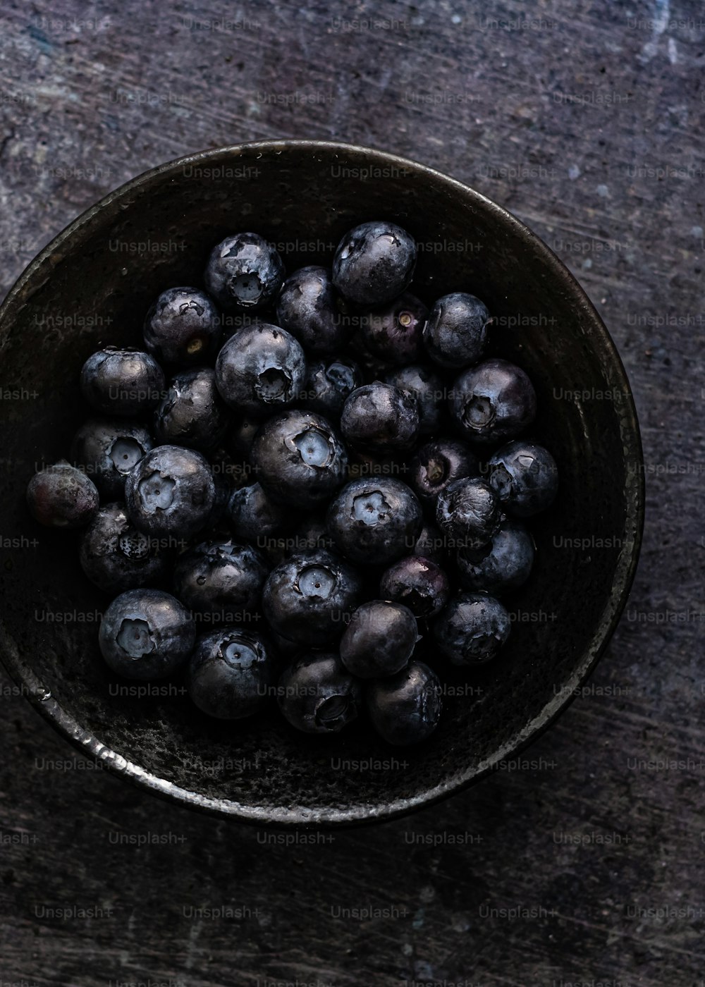 a bowl filled with blueberries on top of a wooden table