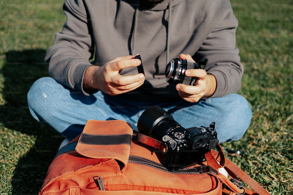 um homem sentado na grama segurando uma câmera