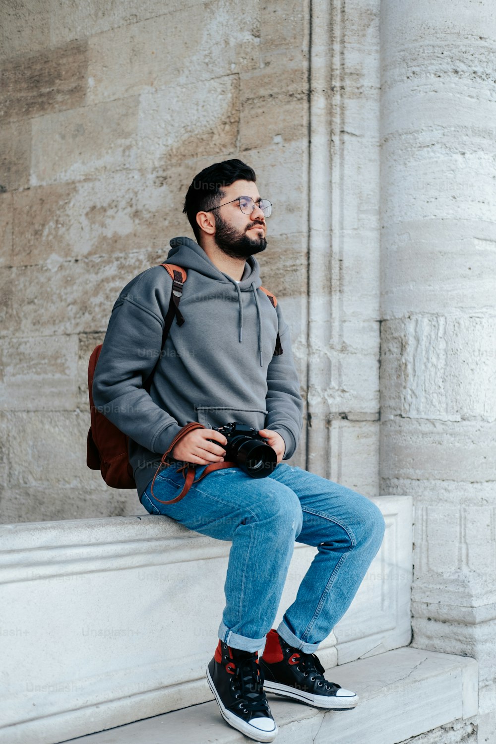 a man sitting on a ledge with a camera