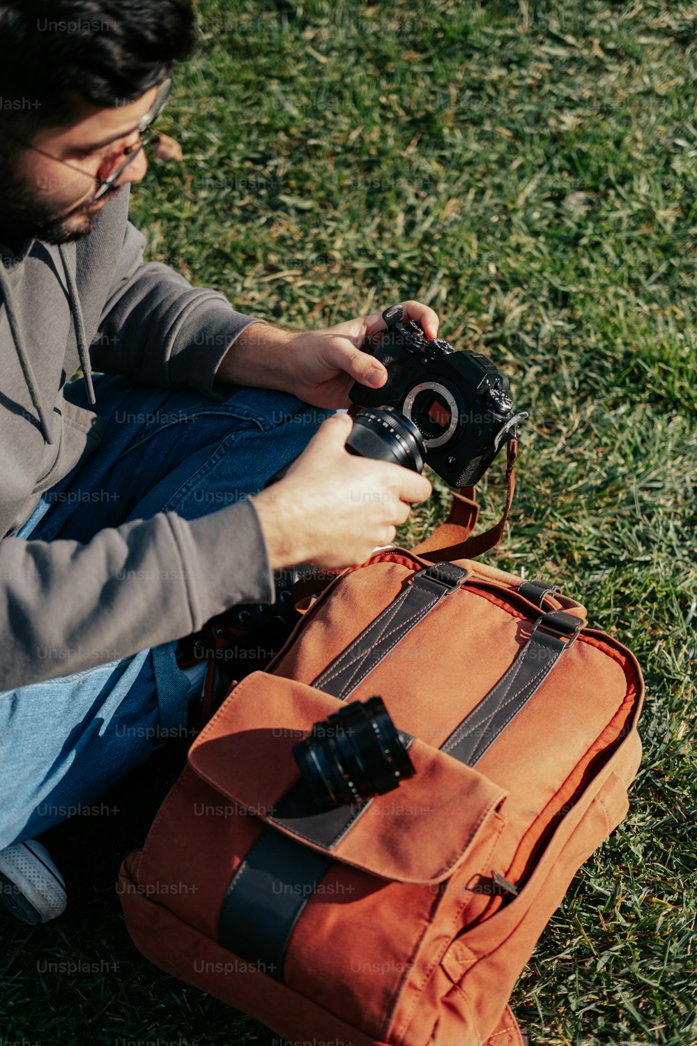 um homem sentado na grama com uma câmera