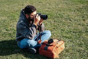 a man sitting in the grass taking a picture with a camera