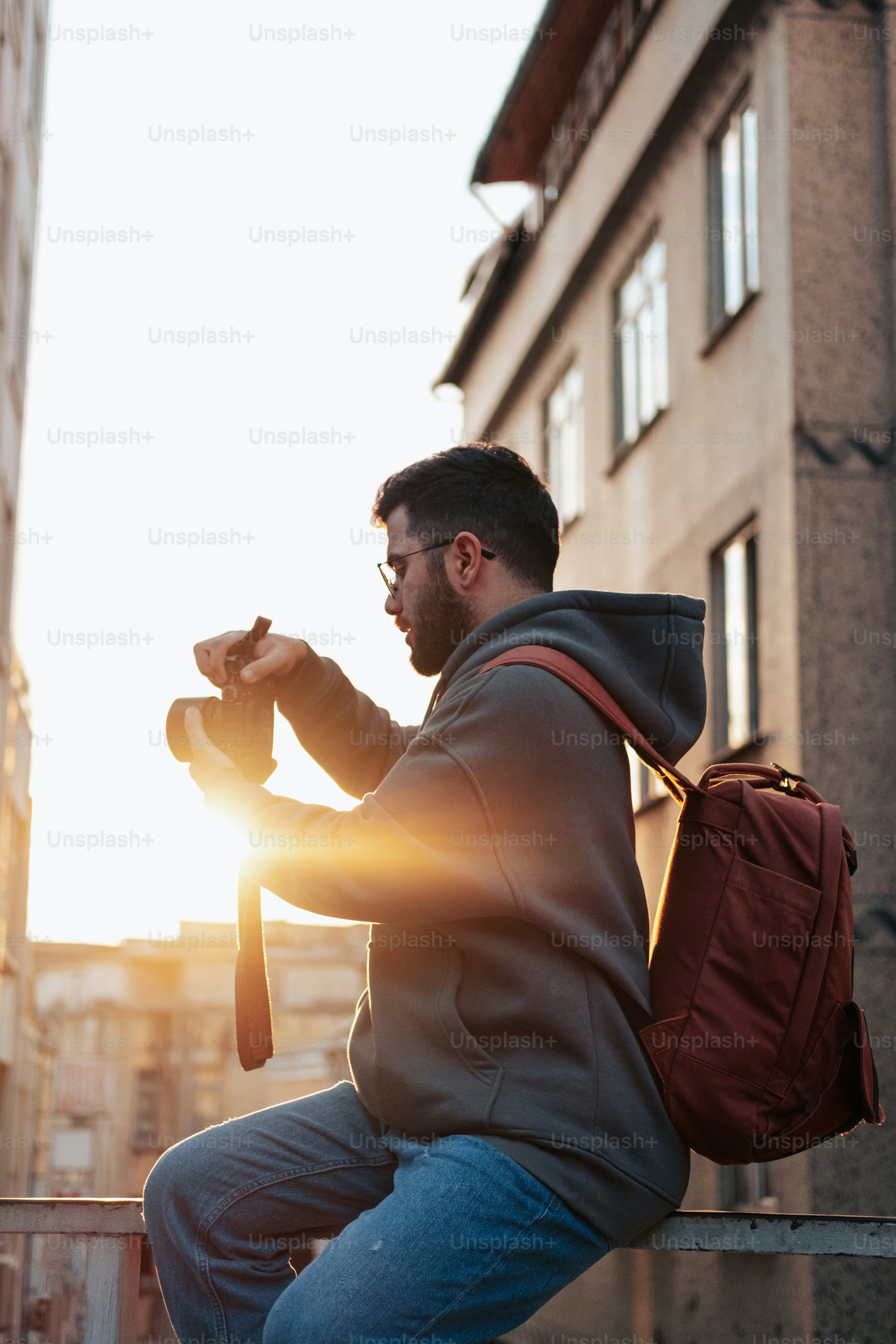 um homem sentado em uma saliência tirando uma foto do sol