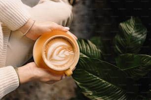 uma mulher segurando uma xícara de café em suas mãos