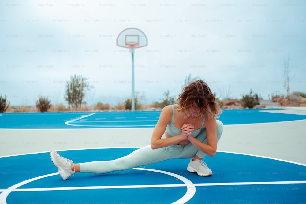 Une femme est assise sur un terrain de basket