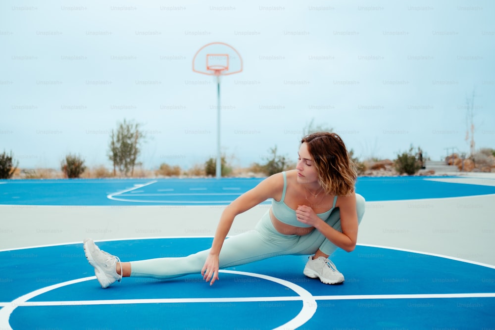 uma mulher está se esticando em uma quadra de basquete