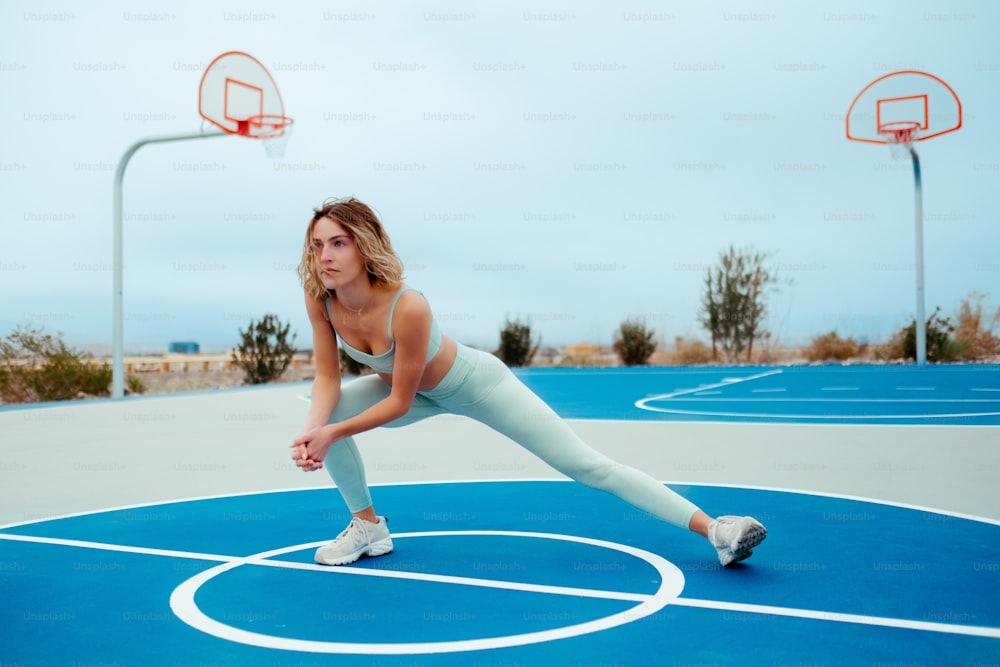 a woman is stretching on a basketball court