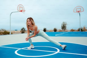 a woman is stretching on a basketball court