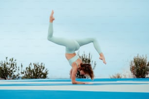 a woman doing a handstand on a blue mat