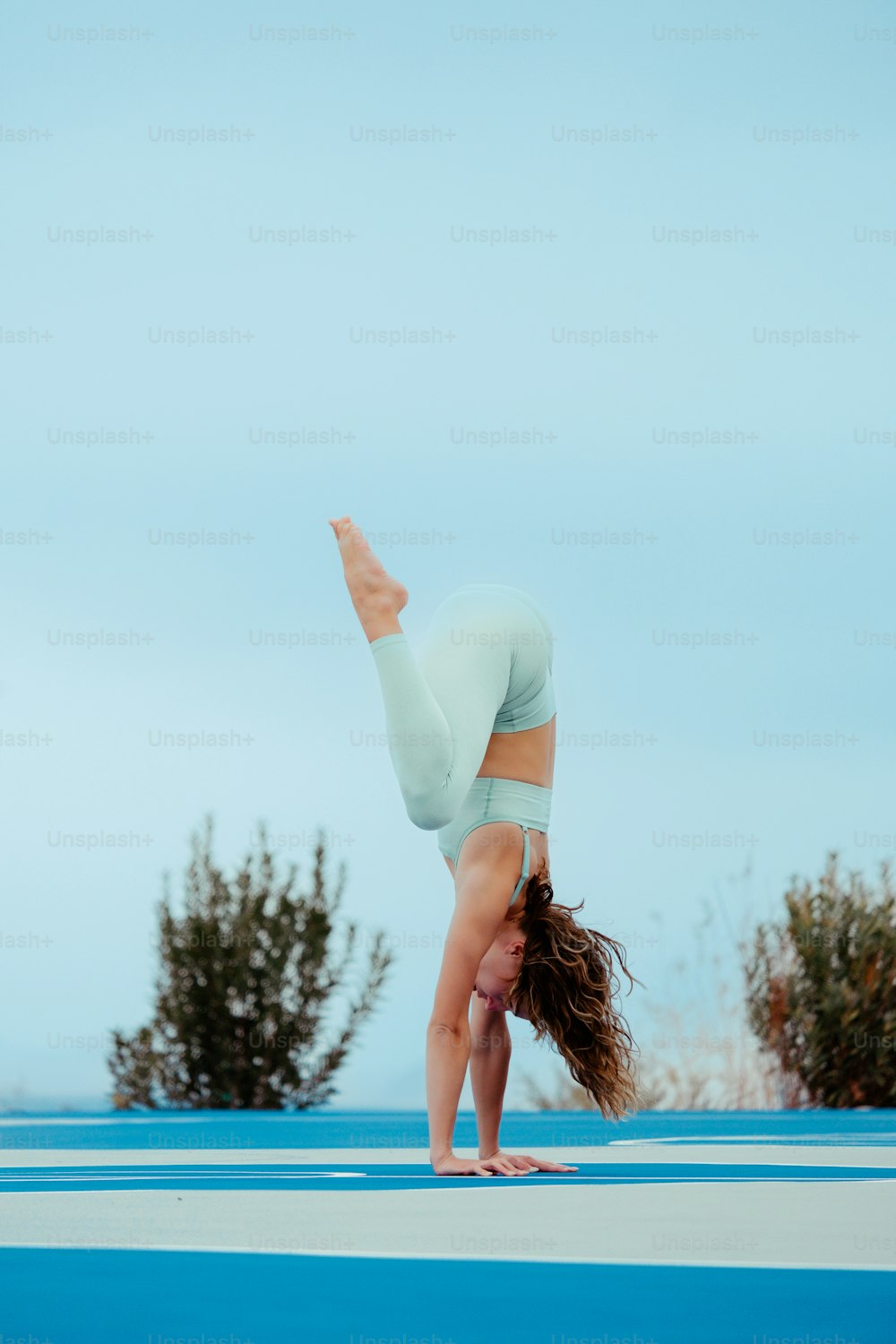 a woman doing a handstand on a blue mat