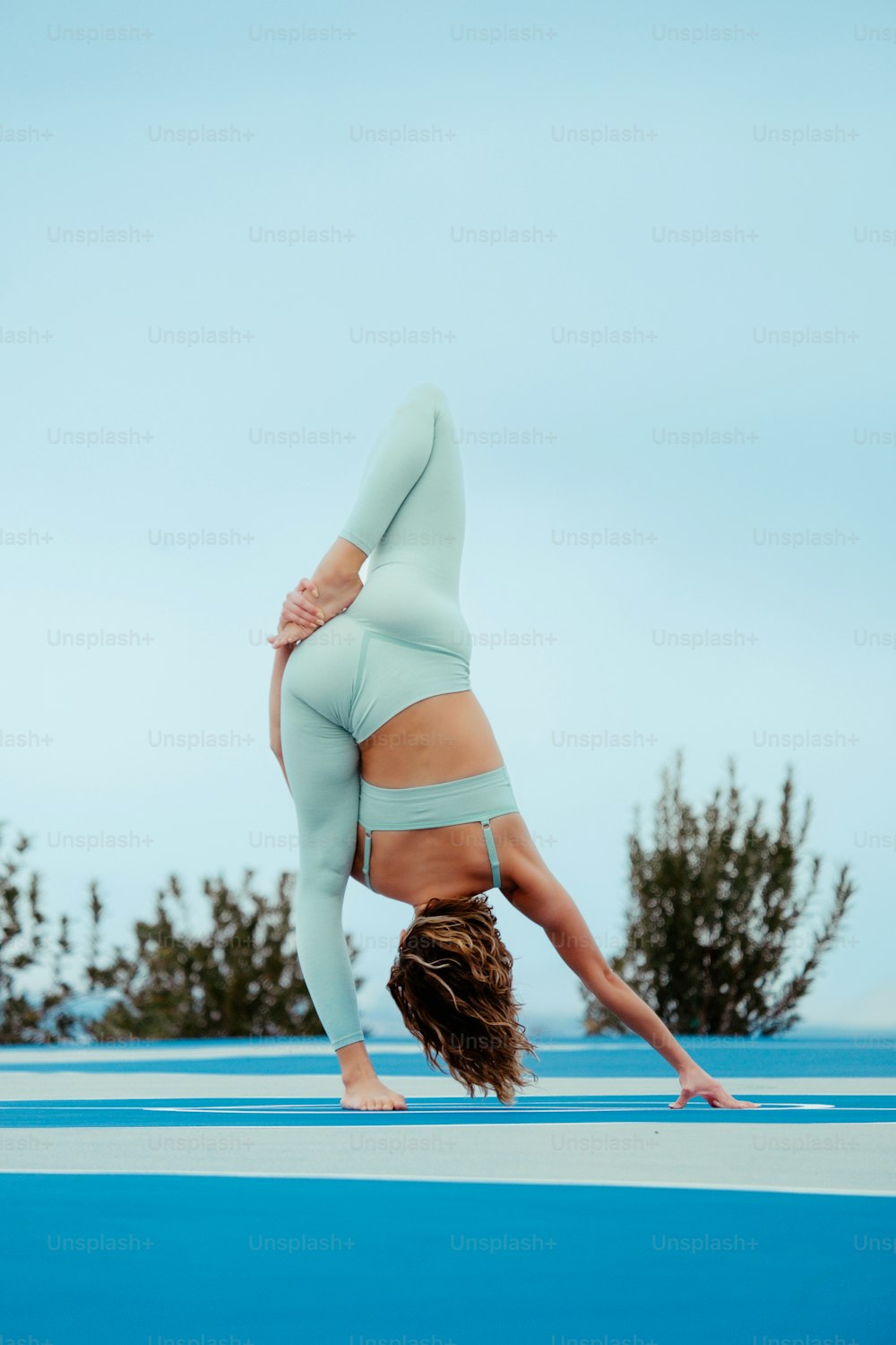 a woman doing a handstand on a blue surface