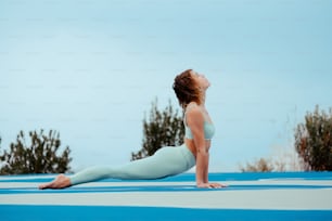 Una donna che fa una posa yoga su una stuoia blu