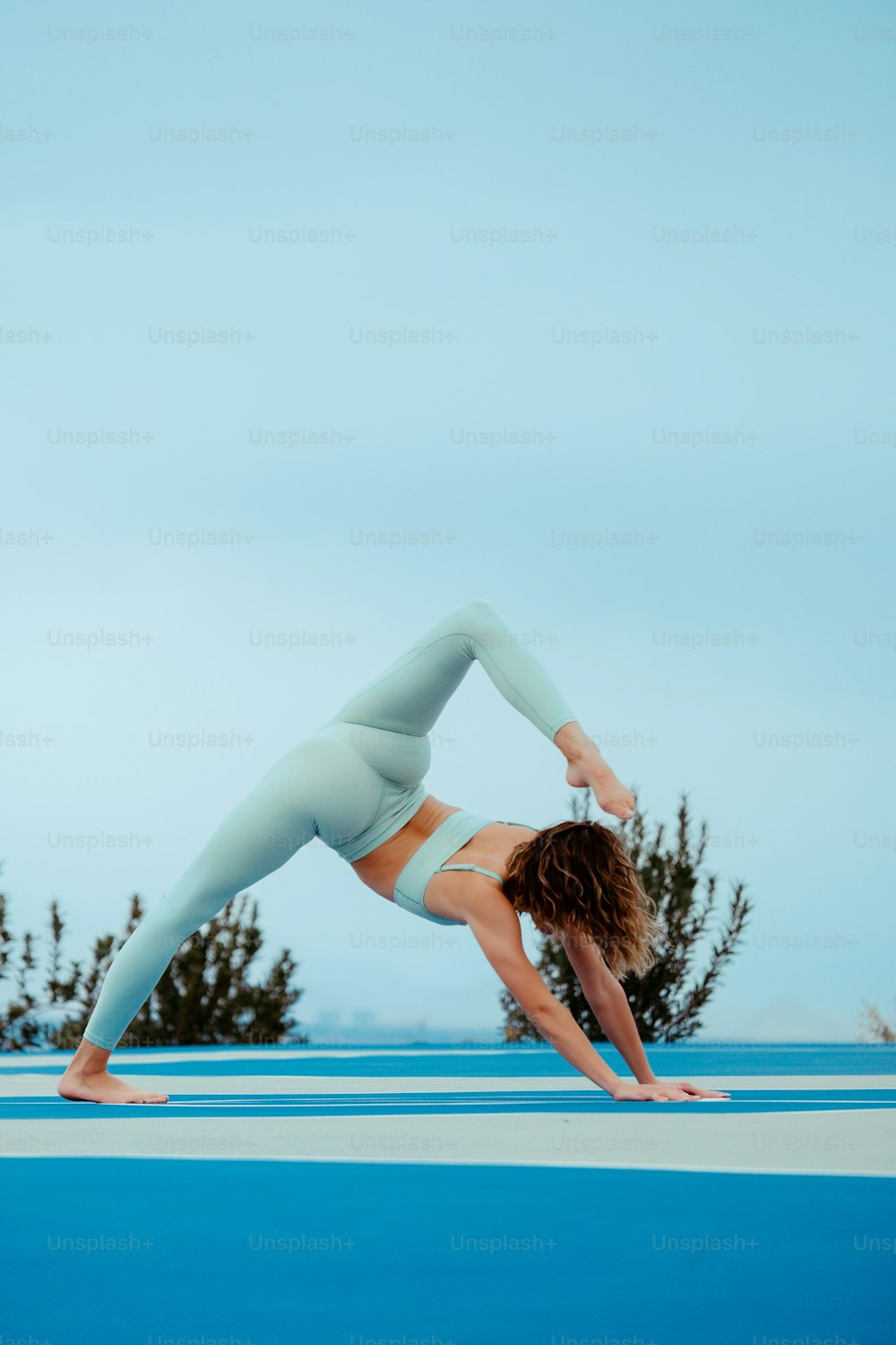 eine Frau, die eine Yoga-Pose auf einer blauen Oberfläche macht