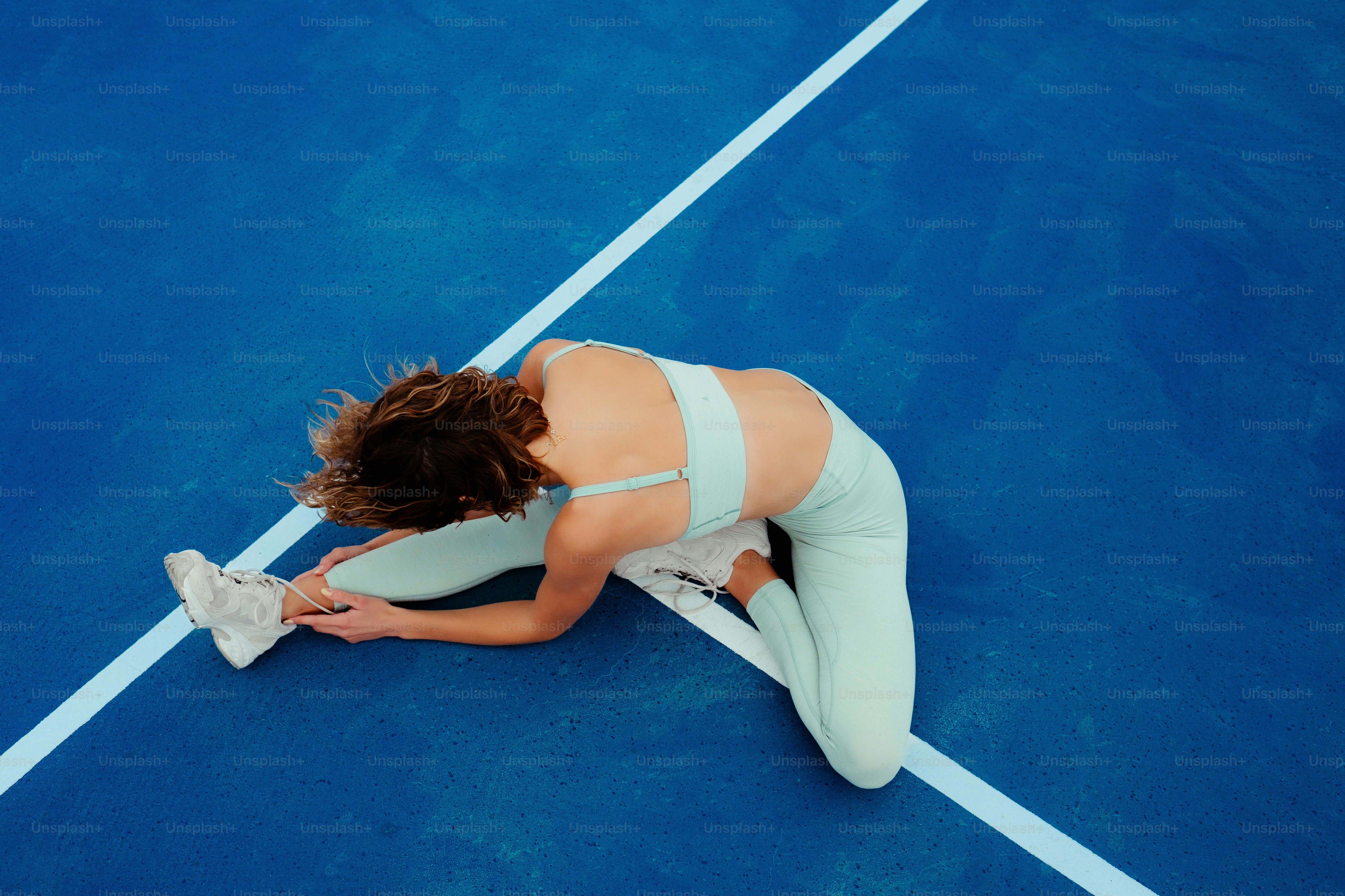 a woman sitting on a tennis court holding a tennis racquet