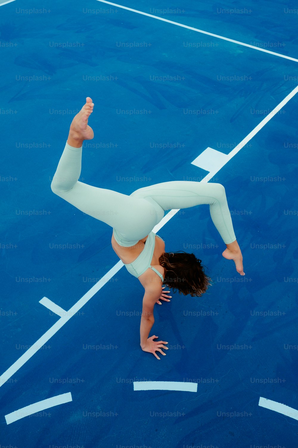 uma mulher está fazendo um handstand em uma quadra de tênis
