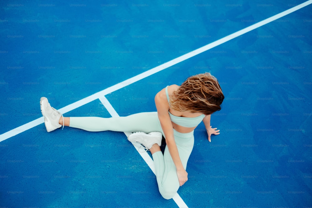 a woman sitting on a blue tennis court