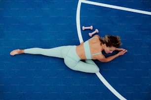 a woman laying on a tennis court holding a tennis racquet