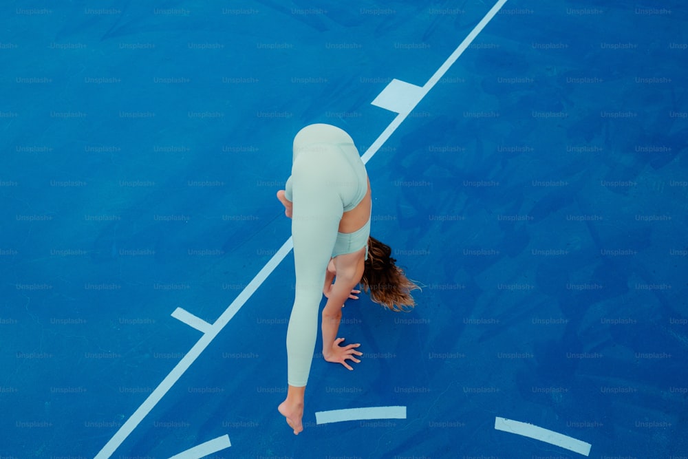 Une femme en tenue blanche est sur un court de tennis bleu