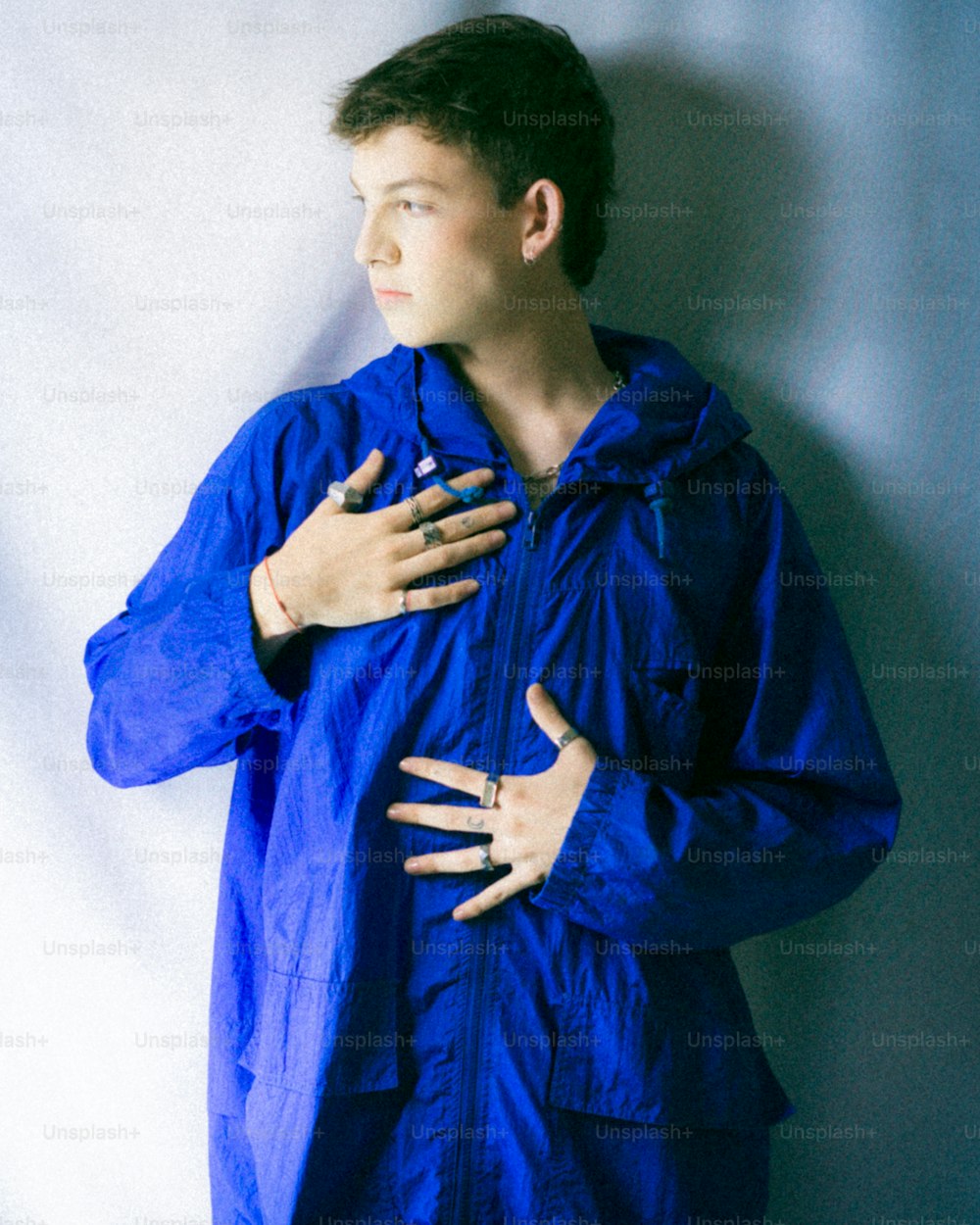a woman in a blue raincoat standing against a wall