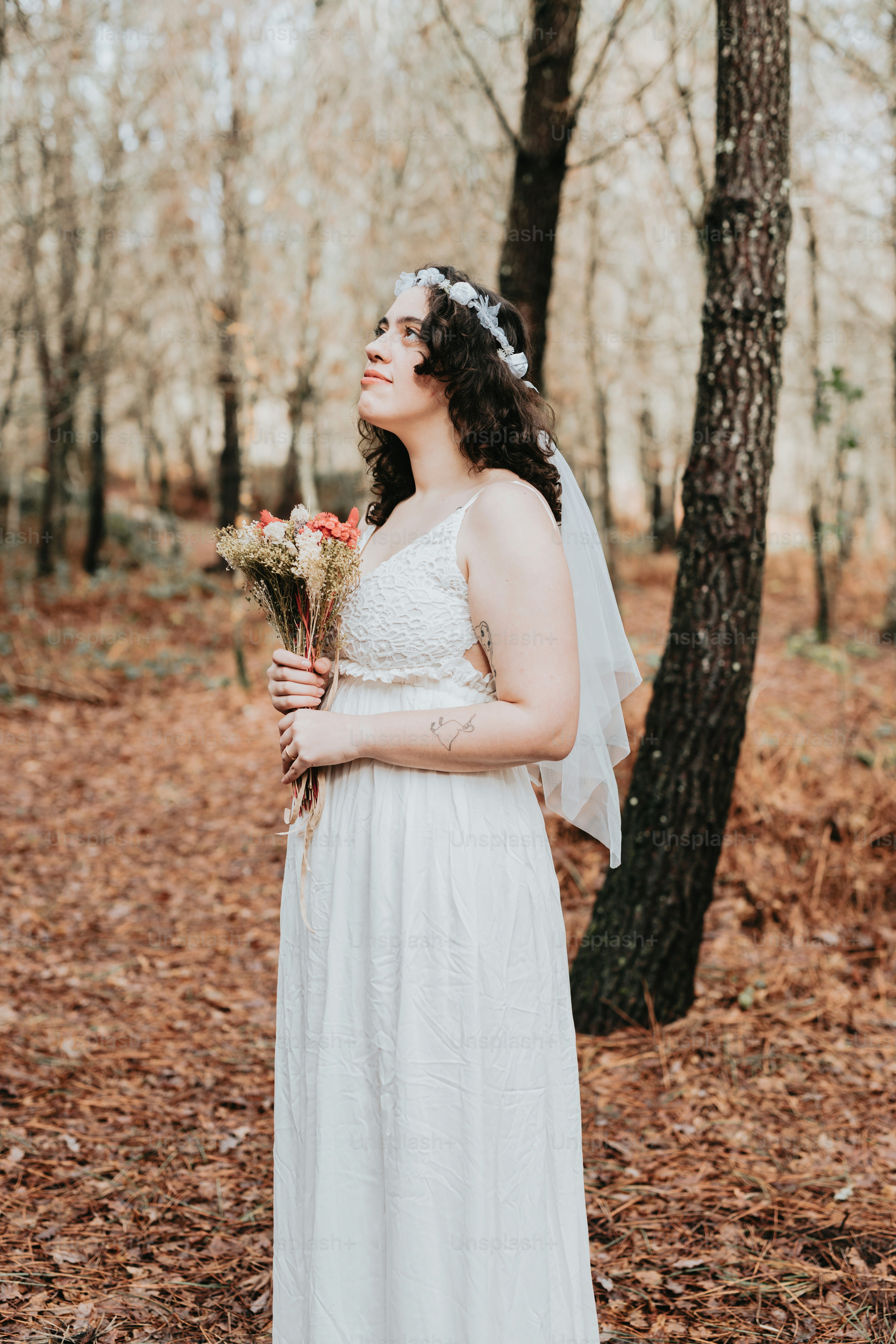 A woman in a white dress holding a bouquet of flowers photo – Wedding ...