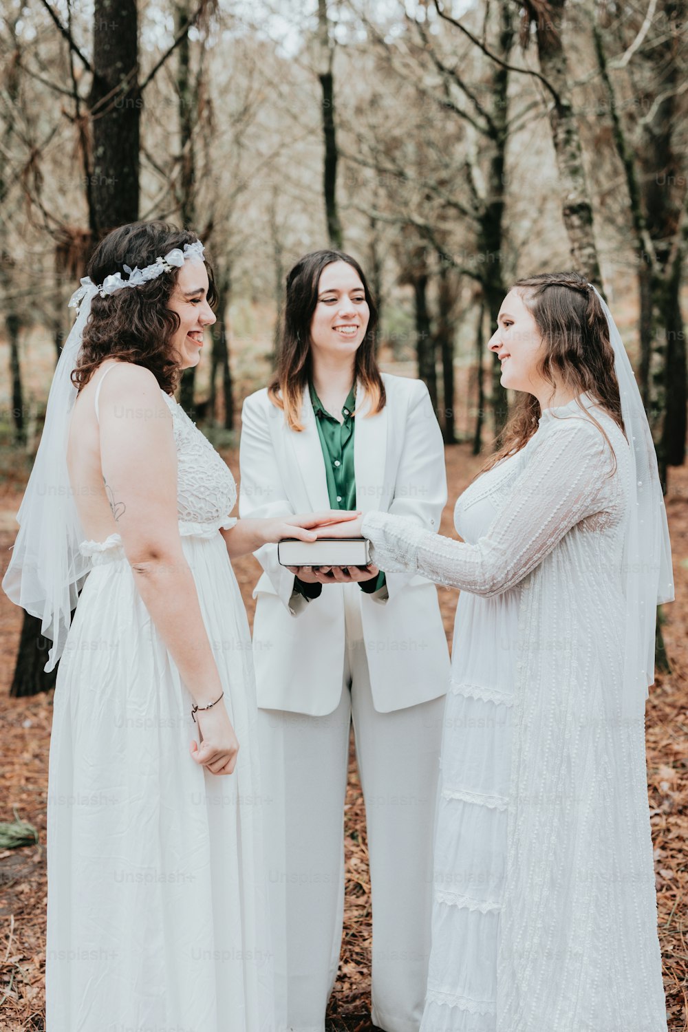 a bride and two bridesmaids standing in the woods