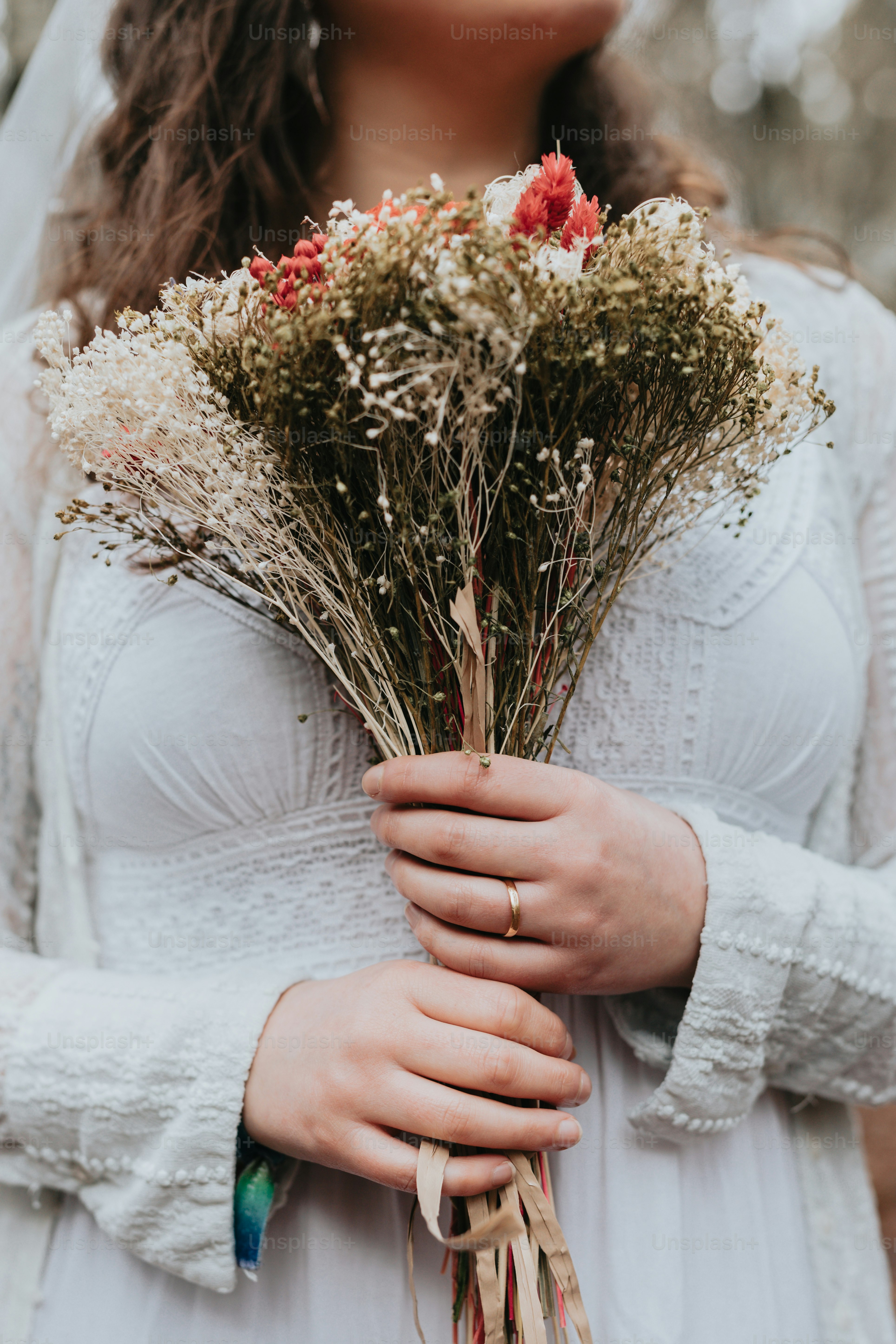 A woman in a white dress holding a bouquet of flowers photo – Bouquet ...